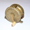 Brass 2" vintage fishing reel with decorative flower swirl to front & back plates to display